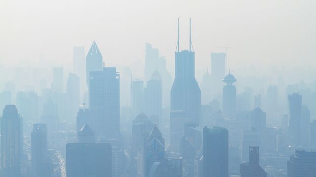 A city skyline obscured by blue-tinted smog.