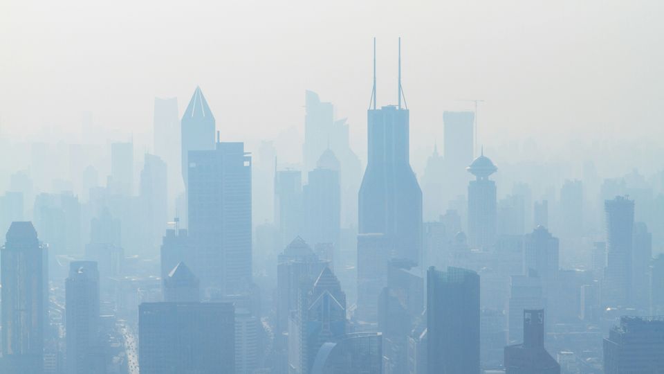 A city skyline obscured by blue-tinted smog.