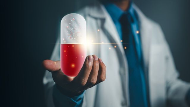 A researcher holding up a hologram of a molecule in a pill, representing AI-driven anti-infective discovery.