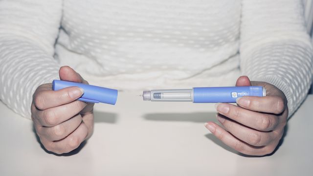 Person holding a GLP-1 injection pen used for managing type 2 diabetes and weight loss.