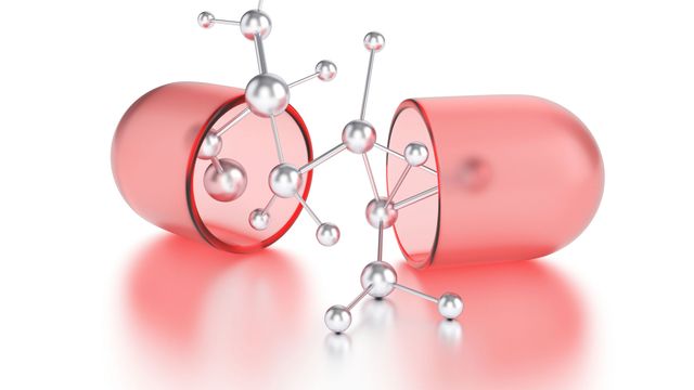 3D stick and ball molecular structure emerging from a red drug capsule.