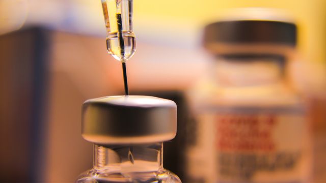 A syringe drawing liquid from a vial containing influenza vaccine.