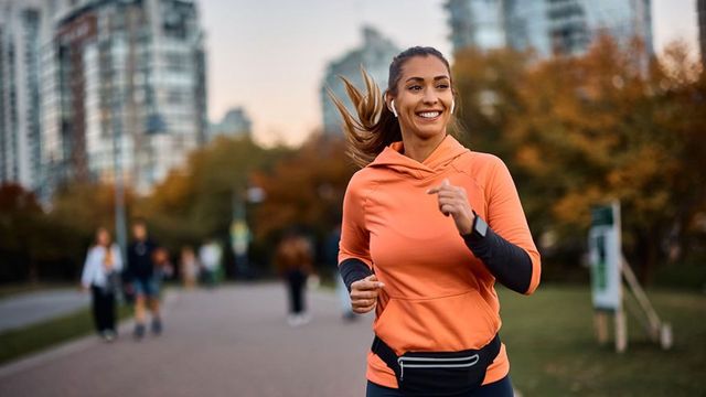 Woman wearing orange hoodie running.