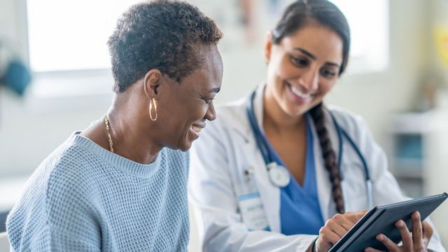 Female doctor talking to patient and showing them a document.