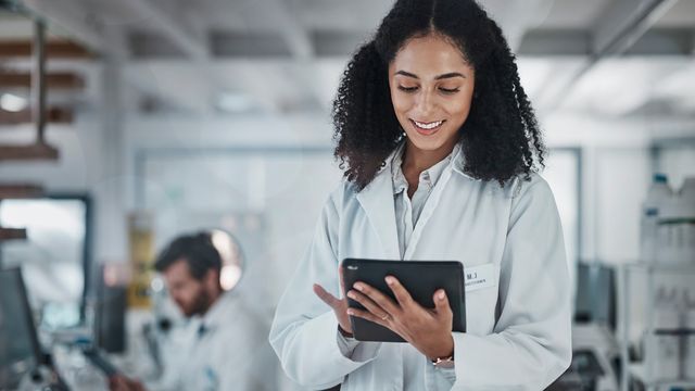 Female scientist in a lab coat using a digital tablet in a modern laboratory.