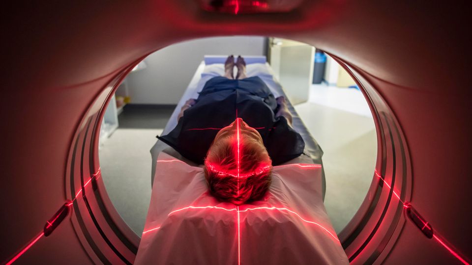 Patient undergoing advanced imaging scan with red laser alignment in a medical scanner.