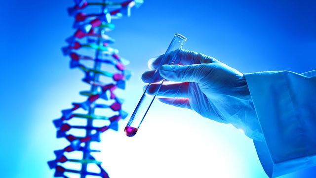 Gloved hand holding test tube beside DNA model, symbolizing biopharma research and innovation.