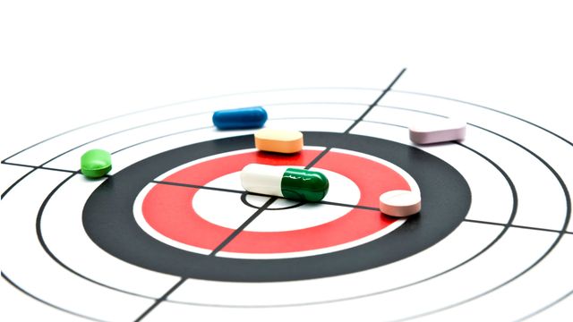 Various drug pills on a target, representing drug target discovery.