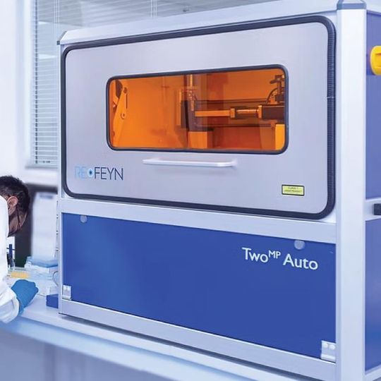 Scientist in lab coat working next to a REFEYN TwoMP Auto instrument in a modern laboratory setting 