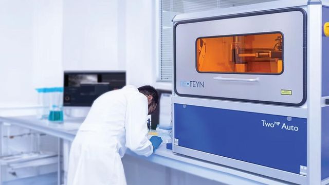 Scientist in lab coat working next to a REFEYN TwoMP Auto instrument in a modern laboratory setting 