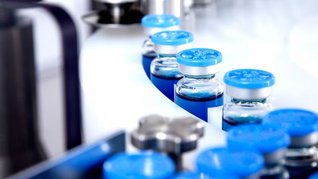 A row of vaccine vials for holding cancer vaccine with blue tops.