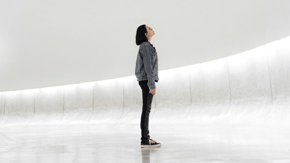 A person standing in a minimalist, modern space, gazing upward, symbolizing curiosity and the future of science.
