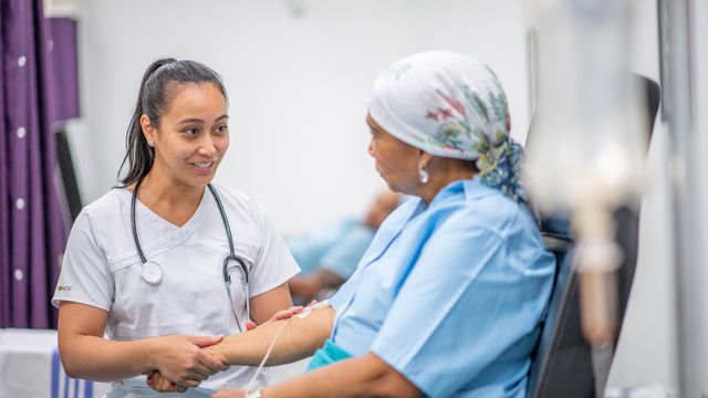 A doctor talking to a cancer patient while they receive cancer therapy via an IV drip. 